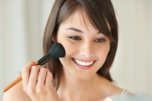 Happy young woman applying make up